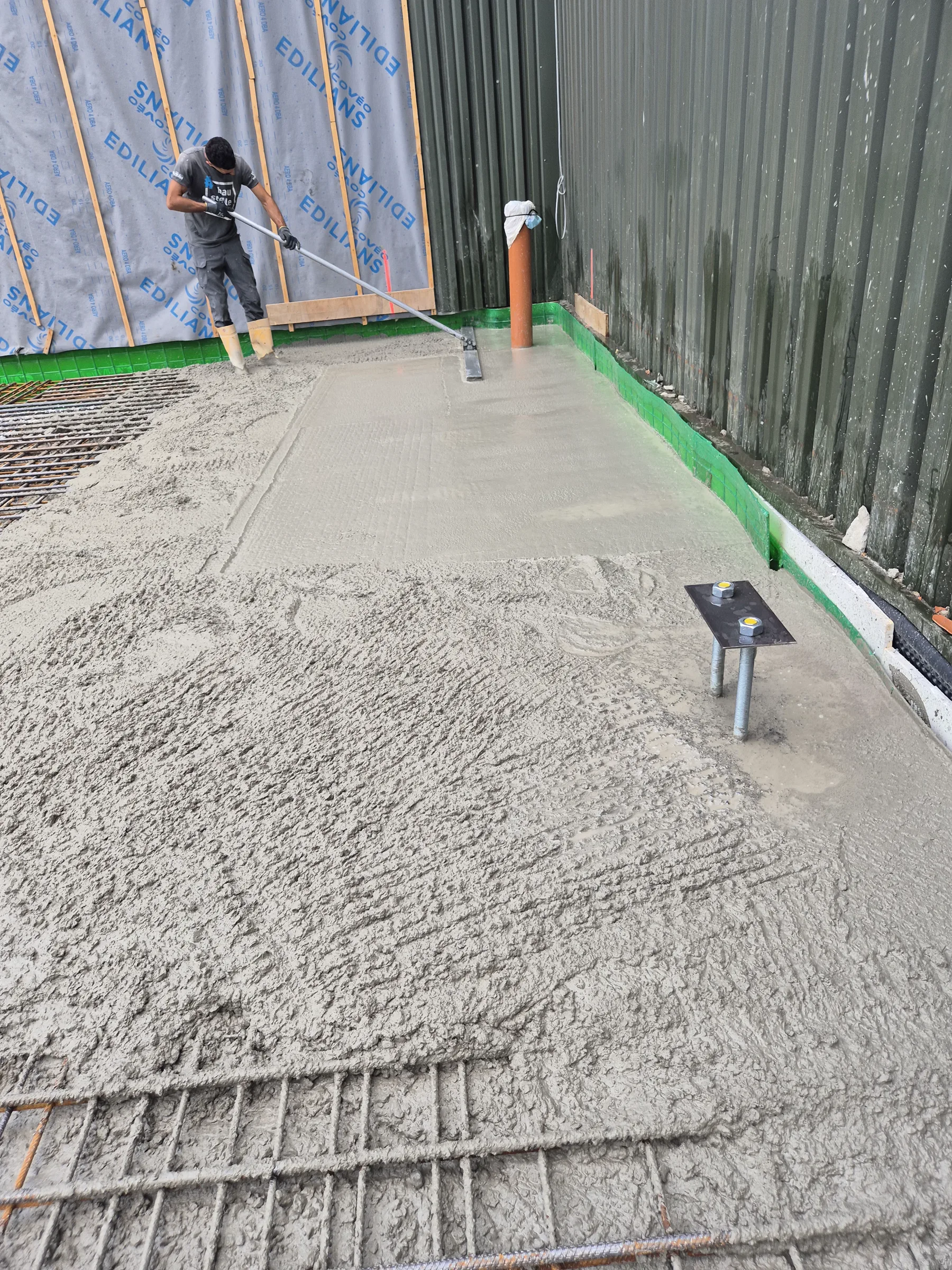 Arbeiter beim Abziehen einer frisch eingebauten Betonfläche